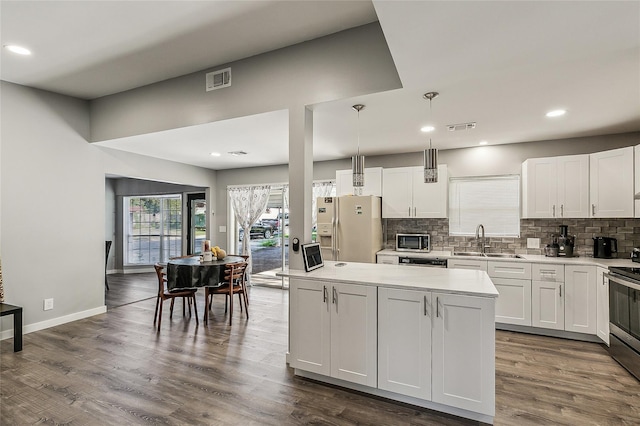 kitchen featuring white cabinetry, pendant lighting, white fridge with ice dispenser, and sink