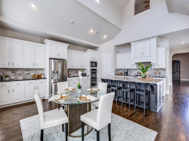 dining space with dark wood-type flooring and high vaulted ceiling