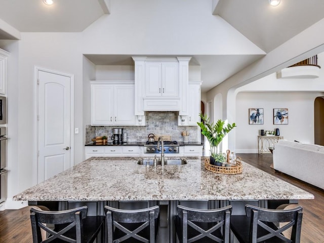 kitchen featuring white cabinetry, a breakfast bar, and a large island with sink