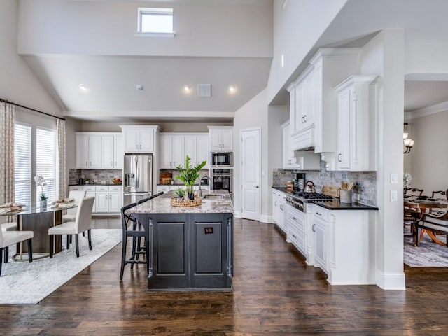 kitchen with white cabinetry, tasteful backsplash, an island with sink, and appliances with stainless steel finishes