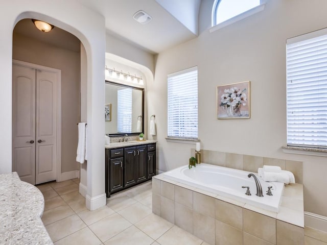 bathroom with tile patterned flooring, vanity, and tiled tub