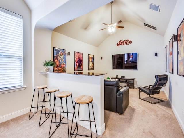 bar featuring light colored carpet, ceiling fan, and vaulted ceiling