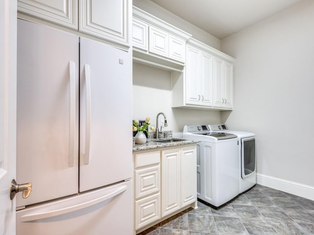 laundry area with cabinets, separate washer and dryer, and sink