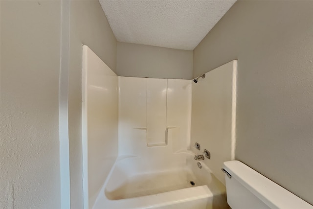 bathroom featuring shower / bathing tub combination, toilet, and a textured ceiling