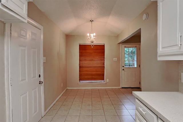 entryway with an inviting chandelier, light tile patterned floors, and a textured ceiling