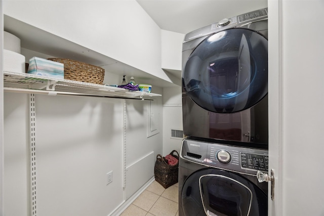 clothes washing area featuring light tile patterned flooring and stacked washer / drying machine