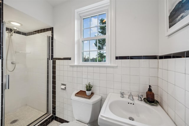 bathroom with tile walls, sink, a shower with shower door, and toilet