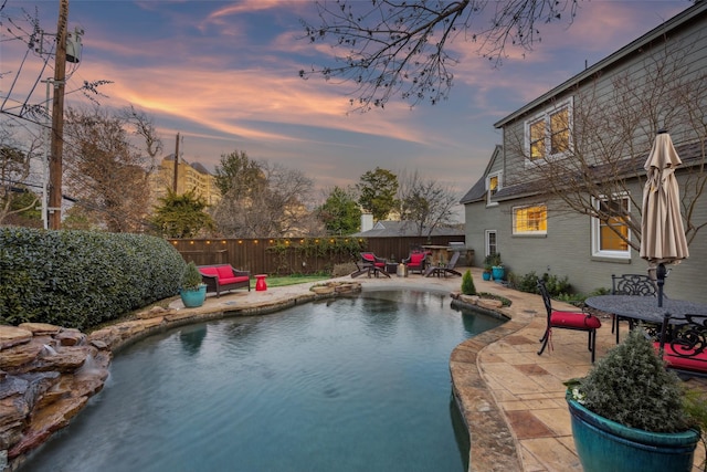 pool at dusk featuring a patio