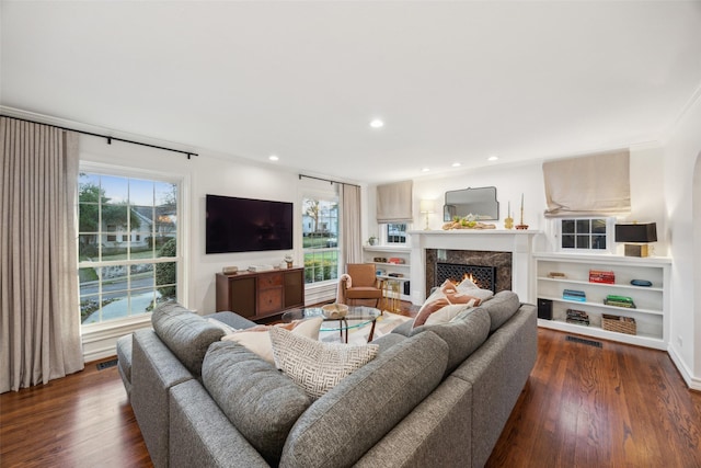 living room featuring ornamental molding, plenty of natural light, dark hardwood / wood-style floors, and a premium fireplace