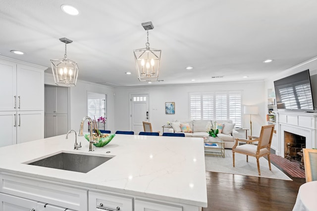 kitchen featuring sink, white cabinets, light stone counters, and decorative light fixtures