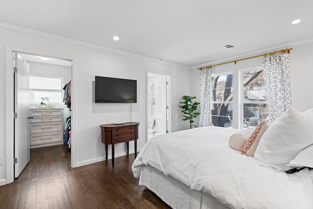 bedroom with connected bathroom, dark hardwood / wood-style flooring, a spacious closet, crown molding, and a closet