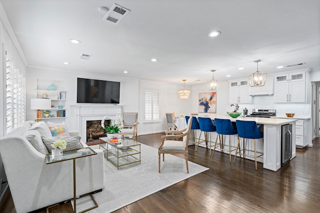 living room featuring ornamental molding, an inviting chandelier, and dark hardwood / wood-style flooring