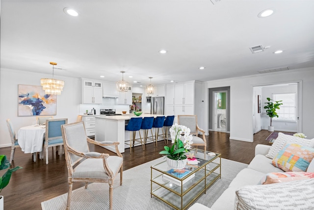 living room featuring ornamental molding, dark hardwood / wood-style floors, and an inviting chandelier