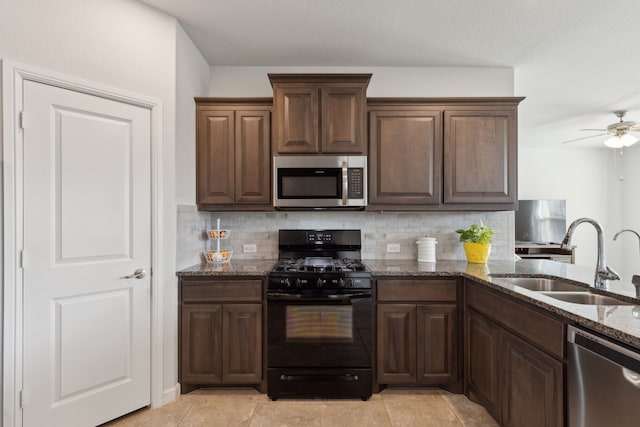 kitchen with sink, dark stone countertops, backsplash, ceiling fan, and stainless steel appliances