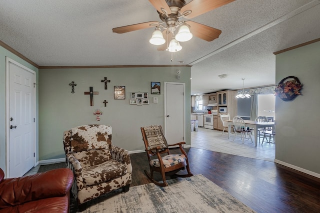 living area featuring lofted ceiling, a textured ceiling, ornamental molding, hardwood / wood-style flooring, and ceiling fan with notable chandelier