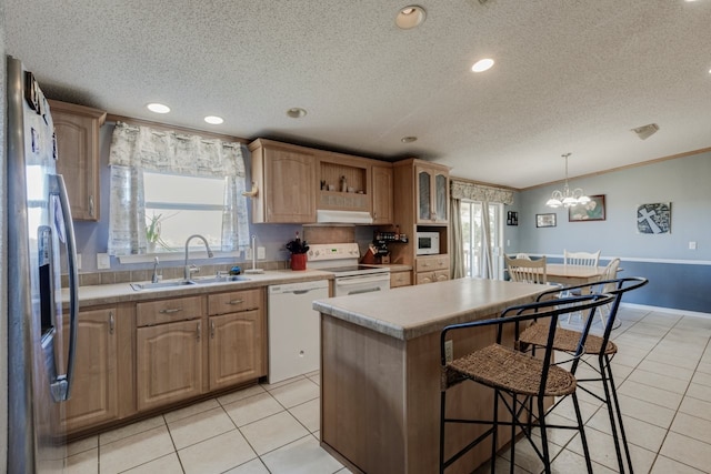 kitchen featuring a kitchen island, sink, hanging light fixtures, crown molding, and white appliances