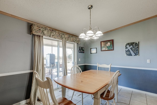 dining space with light tile patterned flooring, ornamental molding, an inviting chandelier, and a textured ceiling