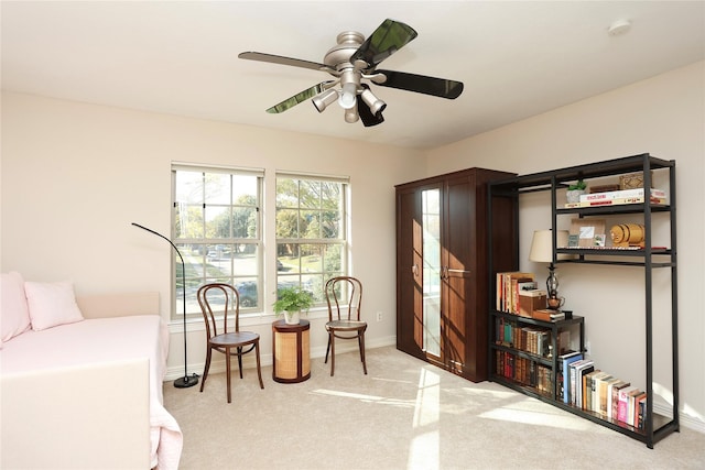 living area with ceiling fan and light carpet