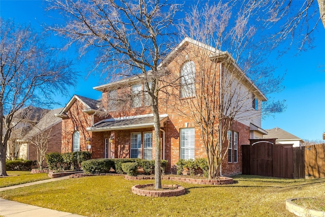 traditional-style house featuring a gate, brick siding, a front yard, and fence