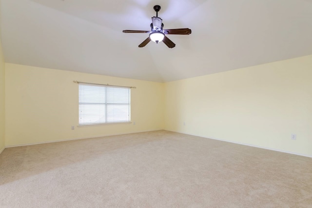 empty room featuring vaulted ceiling, light colored carpet, and ceiling fan