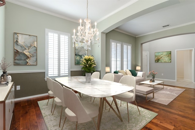 dining space with crown molding, dark hardwood / wood-style flooring, and an inviting chandelier