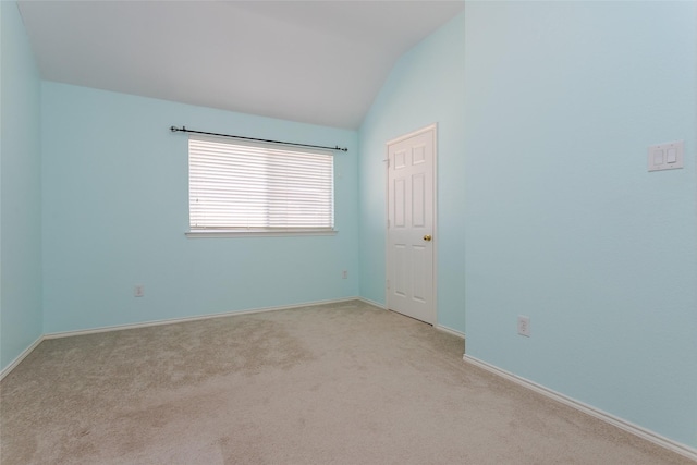 carpeted spare room featuring vaulted ceiling