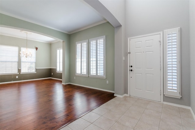 foyer featuring ornamental molding, light tile patterned floors, and an inviting chandelier