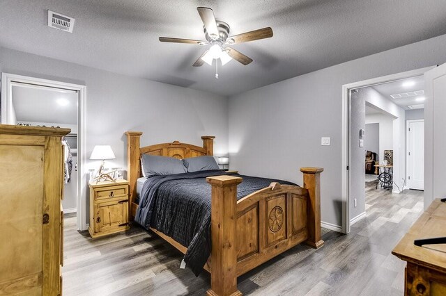 bedroom featuring a textured ceiling, ceiling fan, and light hardwood / wood-style flooring