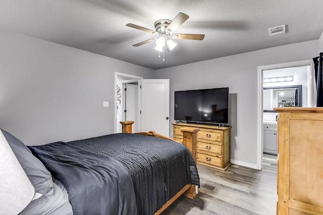 bedroom featuring connected bathroom, hardwood / wood-style floors, a textured ceiling, and ceiling fan