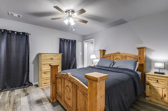 bedroom with hardwood / wood-style floors, a textured ceiling, and ceiling fan