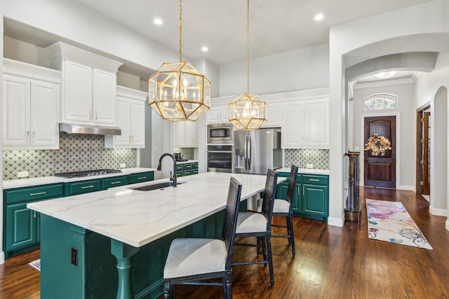 kitchen with sink, white cabinetry, appliances with stainless steel finishes, an island with sink, and decorative backsplash