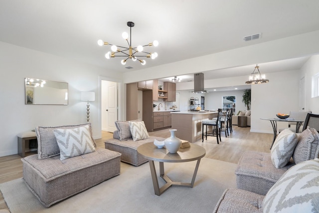 living room with sink, light hardwood / wood-style floors, and a chandelier