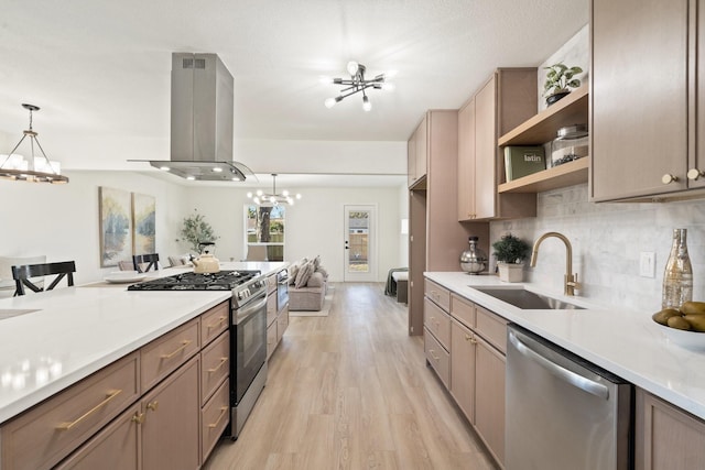 kitchen featuring appliances with stainless steel finishes, sink, hanging light fixtures, island exhaust hood, and an inviting chandelier