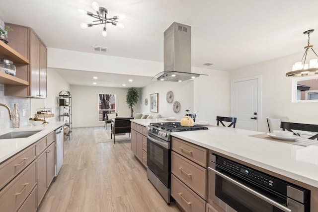 kitchen featuring sink, decorative light fixtures, appliances with stainless steel finishes, a notable chandelier, and island exhaust hood