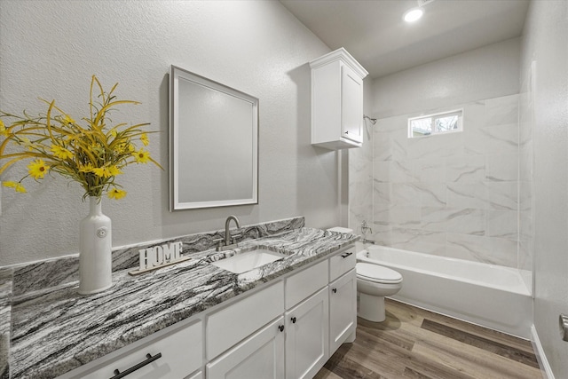 full bathroom featuring hardwood / wood-style flooring, tiled shower / bath, vanity, and toilet