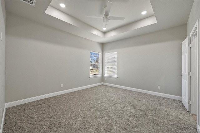 unfurnished room featuring ceiling fan, carpet flooring, and a tray ceiling