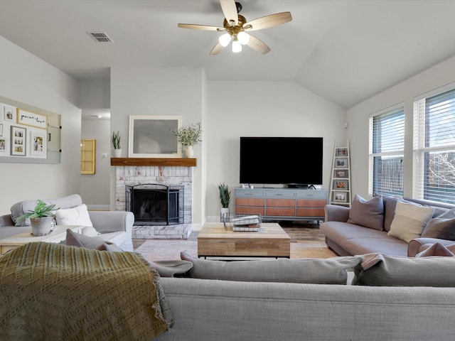 living room featuring a stone fireplace, vaulted ceiling, and ceiling fan