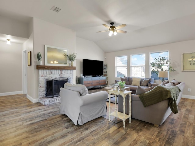 living room with hardwood / wood-style flooring, ceiling fan, vaulted ceiling, and a fireplace