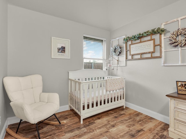 bedroom with hardwood / wood-style floors and a crib