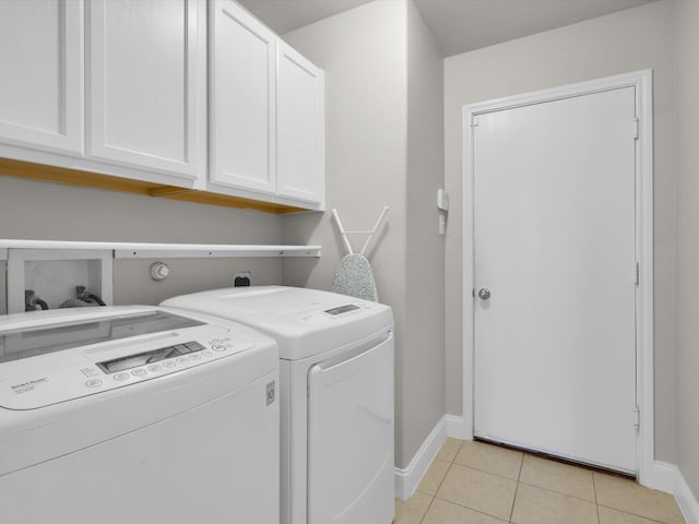 clothes washing area with light tile patterned floors, cabinets, and washing machine and clothes dryer