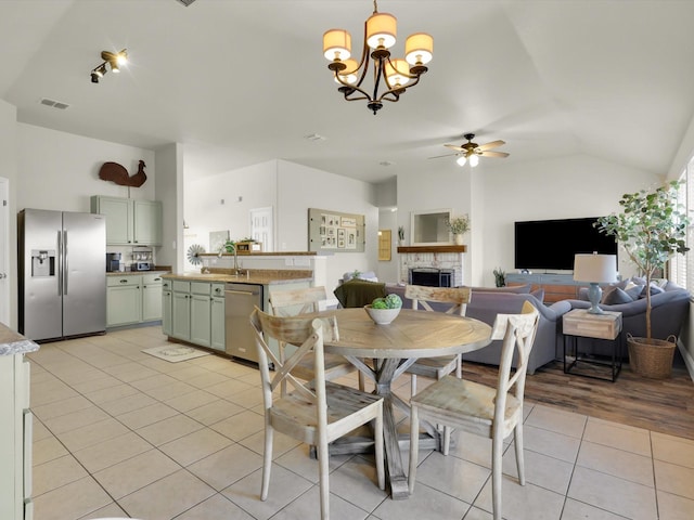 tiled dining space featuring ceiling fan, lofted ceiling, and a brick fireplace