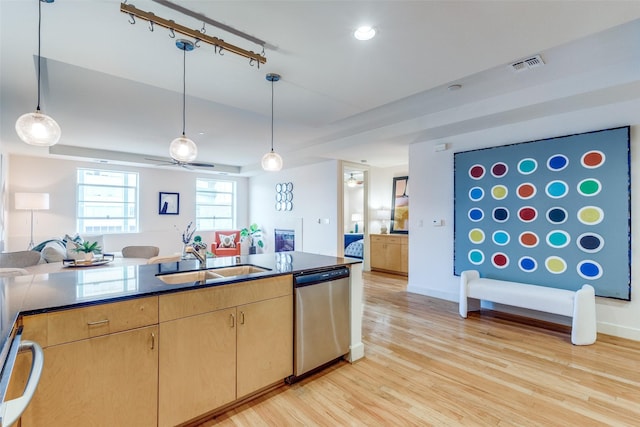 kitchen featuring sink, light wood-type flooring, light brown cabinets, stainless steel dishwasher, and pendant lighting