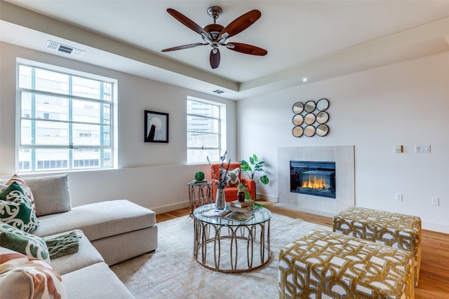 living room with a tiled fireplace, light hardwood / wood-style floors, and a wealth of natural light