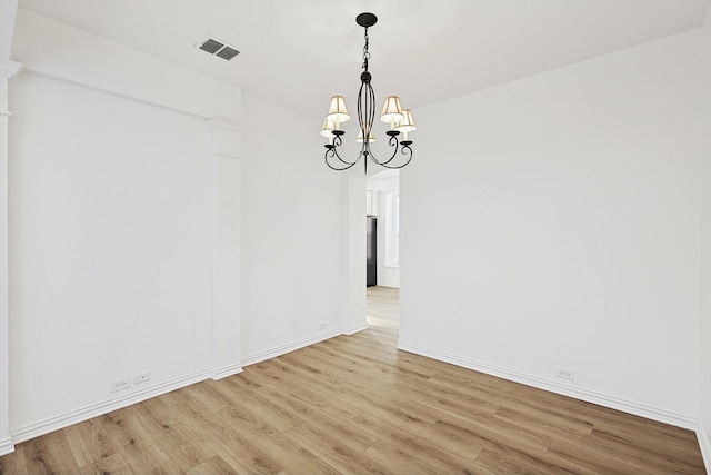 unfurnished dining area featuring an inviting chandelier and light hardwood / wood-style flooring