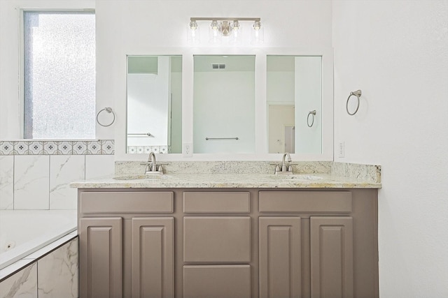 bathroom featuring vanity and tiled bath