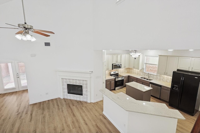 kitchen with light stone counters, white cabinetry, appliances with stainless steel finishes, a tile fireplace, and a kitchen island