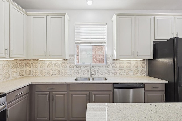 kitchen with sink, white cabinetry, black fridge, tasteful backsplash, and stainless steel dishwasher