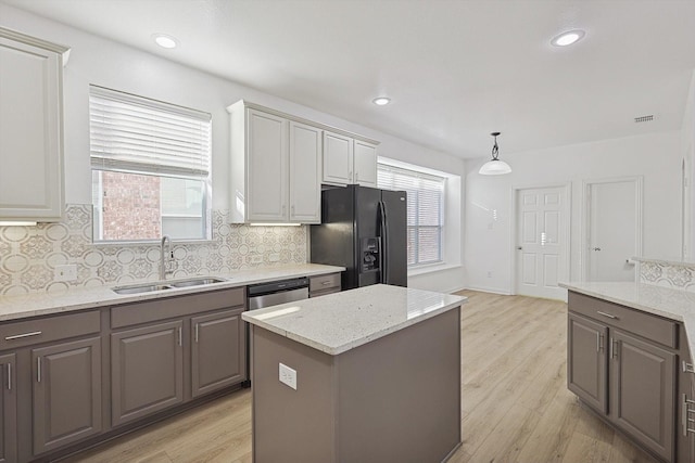 kitchen with black fridge with ice dispenser, sink, light wood-type flooring, pendant lighting, and backsplash