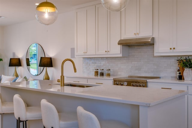 kitchen with sink, range, light stone countertops, white cabinets, and decorative backsplash