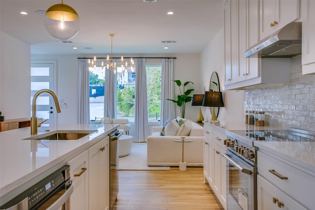 kitchen featuring white cabinetry, stainless steel appliances, sink, and hanging light fixtures